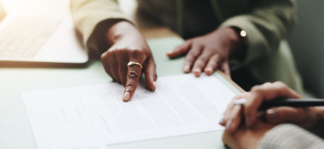 Business people, hands and pointing on contract for legal documents, application and agreement in office. Pen, closeup and person explain paperwork for policy, form or deal in workplace or company